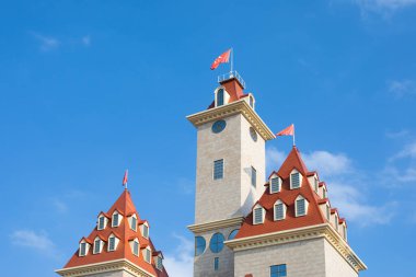 Moskova eğlence parkındaki yeni Rüya Diyarı 'nın dışındaki dekoratif bir şatonun kuleleri. Bir sürü penceresi ve kırmızı bayrağı olan kahverengi kiremitli çatılar. Açık mavi gökyüzüne karşı yüksek ana kule.
