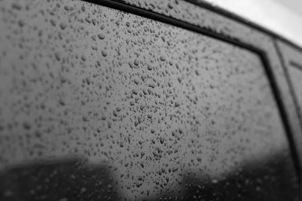 Wet car glass with frame. Black glass surface with raindrops. Natural texture of rain drops on glass, backdrop background for design