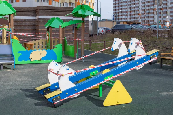 Moskova, Rusya - 5 Nisan 2020: salgın, koronavirüsü durdurun, evde kalın. Dışarıda oyun parkı salıncağı kırmızı kurdeleyi yasaklıyor. Enfeksiyonu durdur Coronavirus virüsü covid-19 sarar