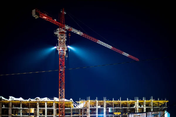 Construction crane, building site lighting at night, construction of an apartment building, beautiful night shot of the construction site