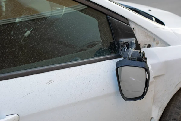 Car mirror broken off, consequences of a car accident. Damage to a car sedan, vandalism, hooliganism, car damage. Torn right side view mirror of the transport