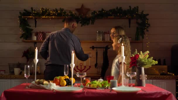 Una familia joven enciende velas en una mesa bellamente decorada en la víspera de año nuevo — Vídeos de Stock