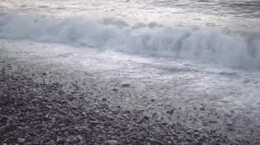 Büyük ve güçlü deniz dalgaları gün batımında kayalık sahilde kopar.