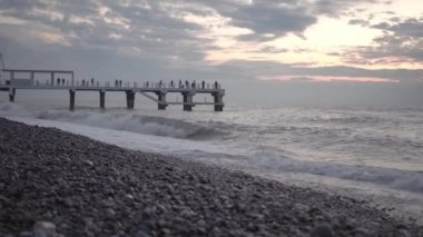 Gün batımında denizin dalgaları kayalık bir sahilde kırılır.