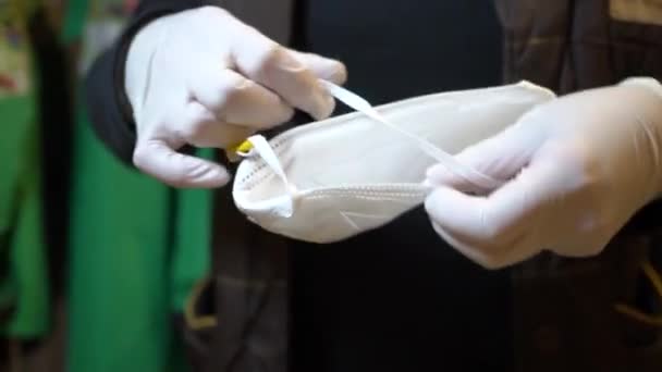 Žena v pracovních šatech, v rukavicích připravuje ochrannou masku na oblékání — Stock video