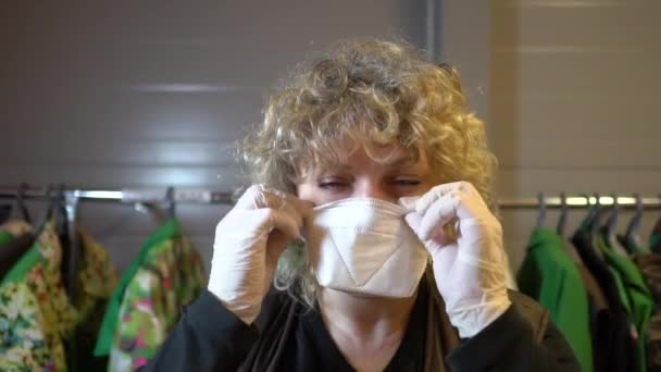 Žena v šatně v ochranných rukavicích si nasadí ochrannou masku. — Stock video