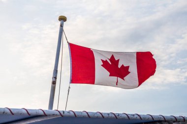 Kanada bayrağı önünde parlak bulutlu gökyüzü rüzgarda uçan. Bir tekne bayrak direği bir güneşli yaz ışığında üzerinde uçan Kanada bayrağı.