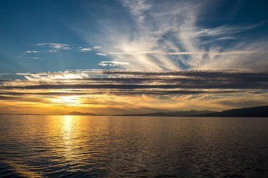 Bulutlu gökyüzünde çılgın turuncu gün batımı. Bulutlar gökyüzünde resim çizerken güneş batıyor.