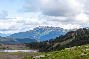 Kuzey Amerika 'nın yüksek karlı dağları manzaralı bulutlar ve altında bir buzul gölü.