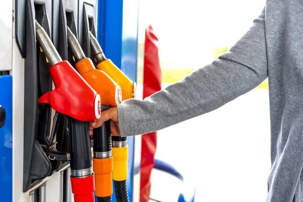 Una mano de mujer toma un arma para repostar un auto en una gasolinera. Vista de cerca . — Foto de Stock