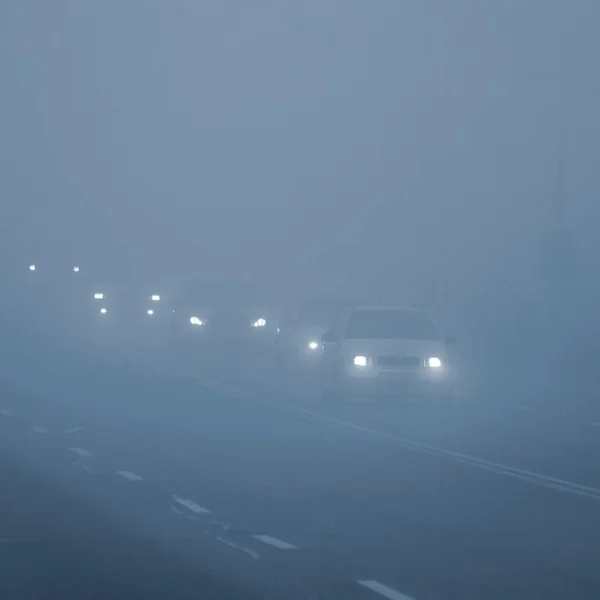 Cars in the fog. Bad winter weather and dangerous automobile traffic on the road. Light vehicles in fog.