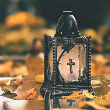 Beautiful autumn concept to the cemetery and Halloween. Candle in a lantern on the grave. Background for Halloween. clipart