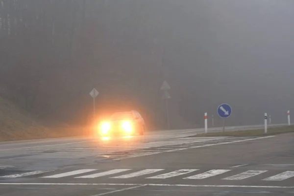 Αυτοκίνητα στην ομίχλη. Κακός χειμώνας και επικίνδυνη κυκλοφορία αυτοκινήτων στο δρόμο. Ελαφρά οχήματα σε ομίχλη. — Φωτογραφία Αρχείου