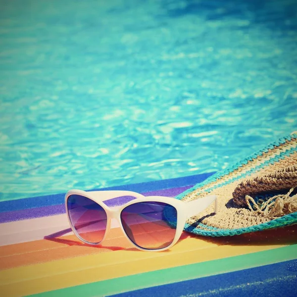 Lilo zonnebril en hoed op het water in warme zonnige dag. De achtergrond van de zomer voor reizen en vakantie. Idyllische vakantie. — Stockfoto