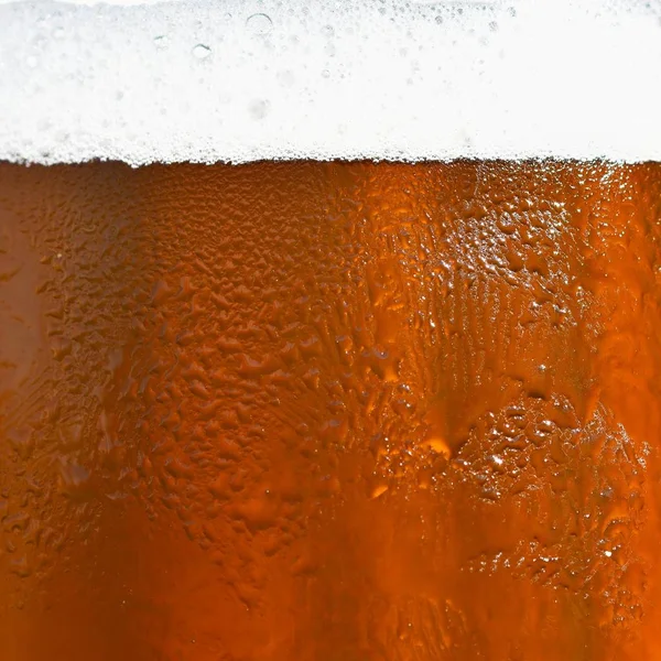 Bier. Mooi detail van geslagen glas bier met schuim. Kleurrijke abstracte achtergrond. — Stockfoto