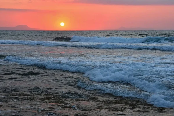 Hermosa puesta de sol de verano junto al mar. Increíble paisaje en la playa con olas y reflejo del sol. Fondo para vacaciones y viajes de vacaciones. Grecia Isla de Creta . — Foto de Stock