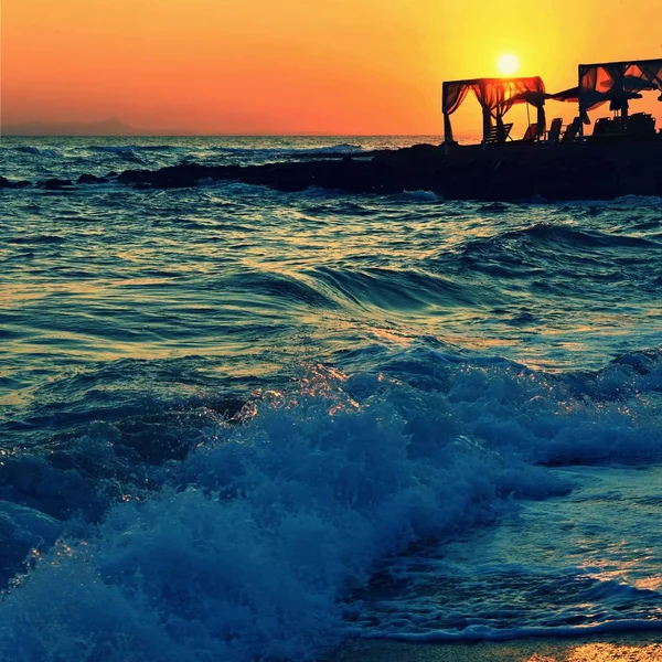 Beautiful summer sunset by the sea. Amazing scenery on the beach with waves and reflection of the sun. Background for holiday and vacation travel. Greece Crete Island. — Stock Photo, Image