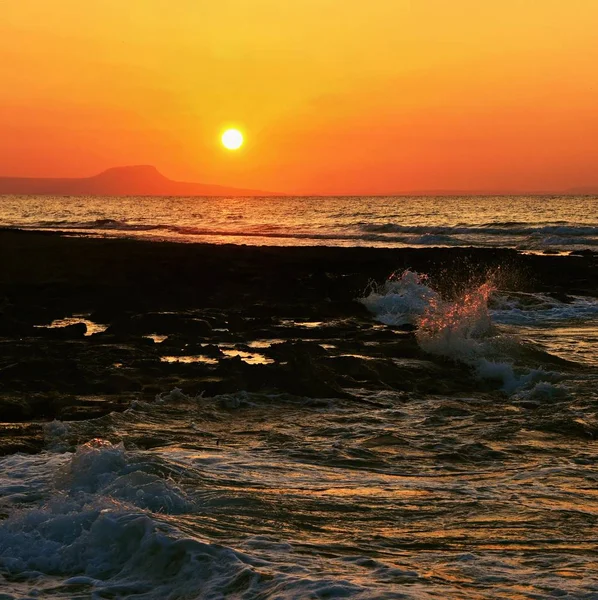 Beautiful summer sunset by the sea. Amazing scenery on the beach with waves and reflection of the sun. Background for holiday and vacation travel. Greece Crete Island. — Stock Photo, Image