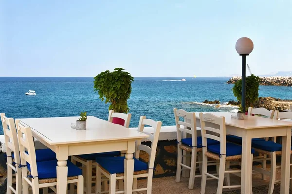 A covered table in a Greek tavern and a sea. Summer background for travel and holidays. — Stock Photo, Image