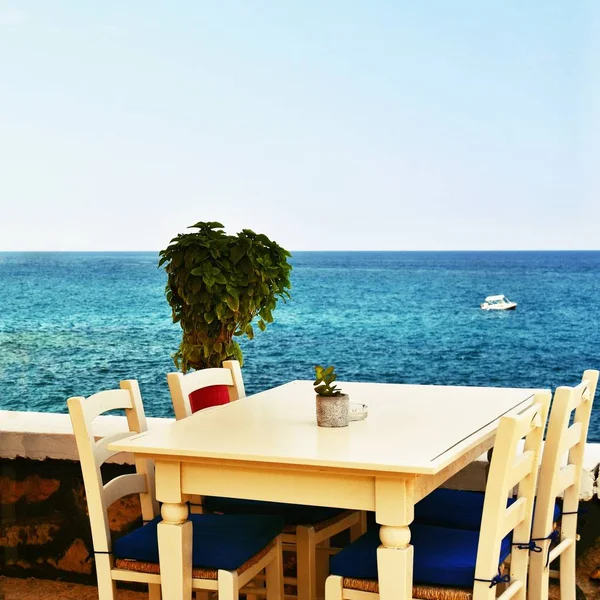 A covered table in a Greek tavern and a sea. Summer background for travel and holidays. — Stock Photo, Image