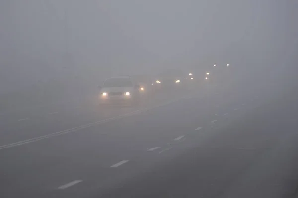 Siste arabalar var. Kötü kış havası ve yolda tehlikeli otomobil trafiği. Siste hafif araçlar. — Stok fotoğraf