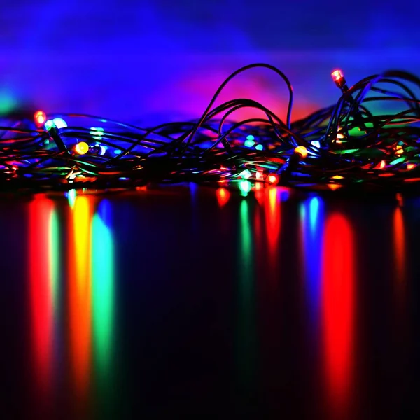 Julbelysning på svart bakgrund med kopieringsutrymme. Färgade reflekterande yta. — Stockfoto