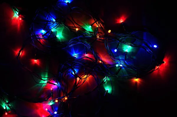 Luces de Navidad sobre fondo negro con espacio para copiar. Superficie reflectante de color. —  Fotos de Stock