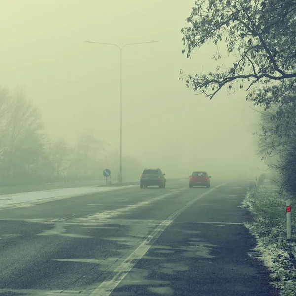 Autos im Nebel. Schlechtes Winterwetter und gefährlicher Autoverkehr auf den Straßen. Fahrzeuge im Nebel. — Stockfoto