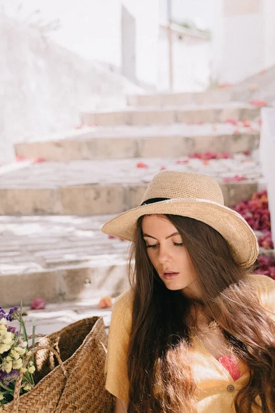 Sarı elbiseli ve uzun kahverengi saçlı bir kız yeşil çiçekli kaktüs ve pembe bougainvillea çiçeklerinin arka planında, Akdeniz 'de tatilde.