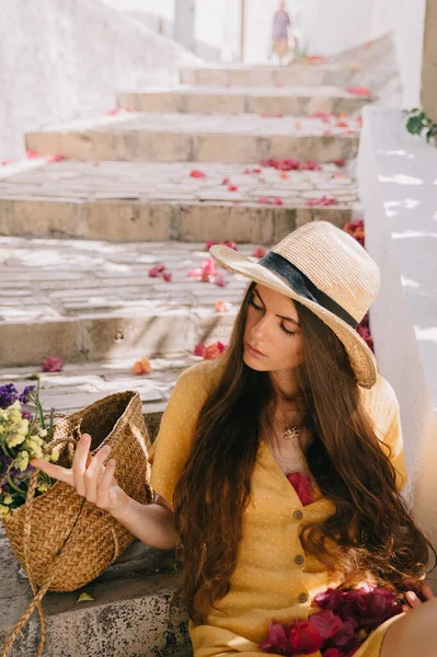 Sarı elbiseli ve uzun kahverengi saçlı bir kız yeşil çiçekli kaktüs ve pembe bougainvillea çiçeklerinin arka planında, Akdeniz 'de tatilde.