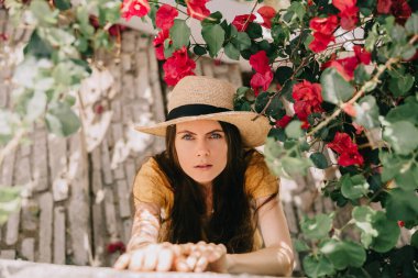 Akdeniz 'de yazın çiçek açan ağaçların altında hasır şapkalı bir kızın portresi. 