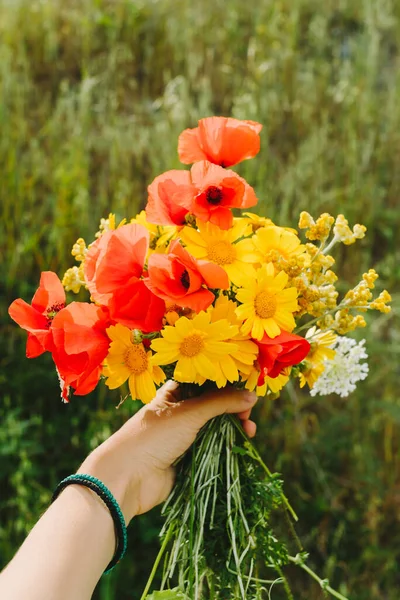 Femme tenant des fleurs sauvages à la main, dans les montagnes d'été, concept de voyage, espace pour le texte . — Photo