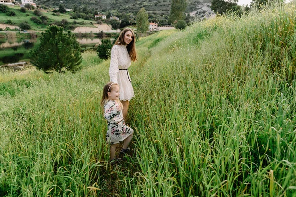 Anne ve kız bebek, mutlu bir aile, açık havada, baharda doğada, dağlarda gülüp oynuyorlar.