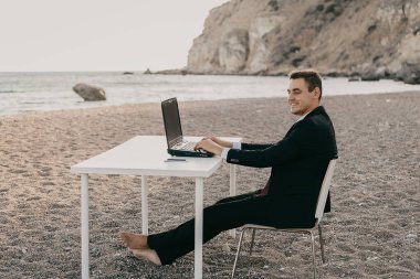 Kumsalda dizüstü bilgisayarı olan bir iş adamı. Serbest çalışan, kumsalda başarılı bir iş adamı.