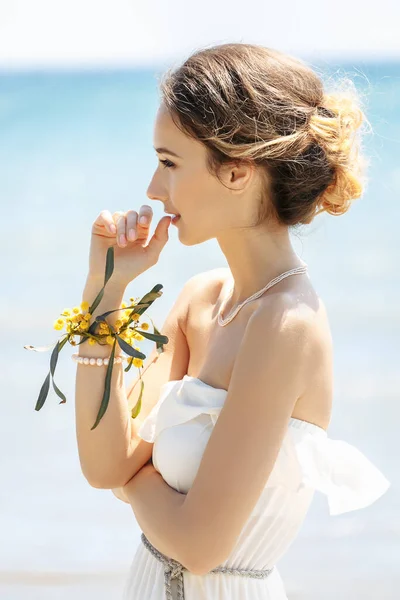 Bride at the sea. Wedding ceremony on the sea, at the beach. Background of sea and mimosa tree . Young bride is dressed in white dress in greek style.