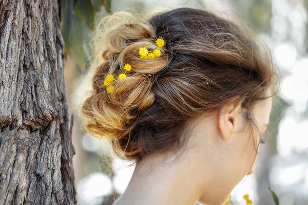 Panna młoda z piękną fryzurą w ogrodzie z żółtym drzewem mimosa. Ceremonia ślubna na morzu. — Zdjęcie stockowe
