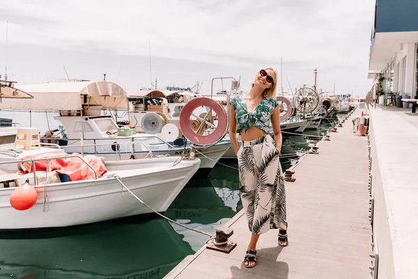 Jolie jeune touriste féminine posant dans le port de la ville méditerranéenne avec des yachts et des bateaux de pêche. Contexte de la mer. Heure d "été — Photo