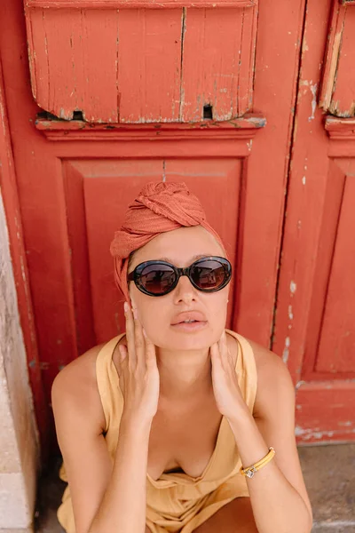 Jolie jeune touriste féminine posant devant une belle porte dans le centre de la vieille ville méditerranéenne, sa coiffure rehaussée de turban — Photo