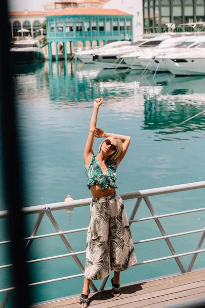Jolie jeune touriste féminine posant dans le port de la ville méditerranéenne avec des yachts de luxe blancs. Contexte de la mer. Heure d "été — Photo