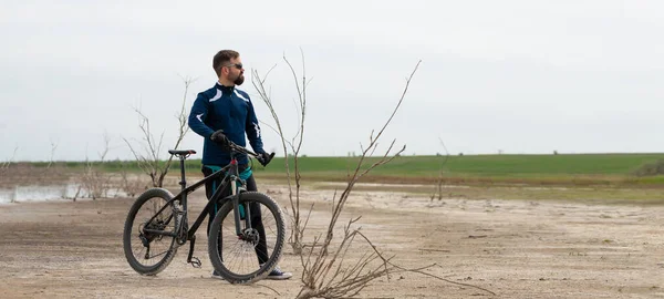 panorama Cyclist on a mountain bike on a salt beach on a background of reeds and a lake