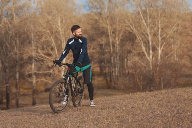 Bisikletçi sonbahar ormanlarında gezer ve park eder.