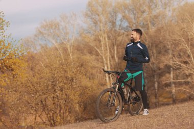 Bisikletçi sonbahar ormanlarında gezer ve park eder.