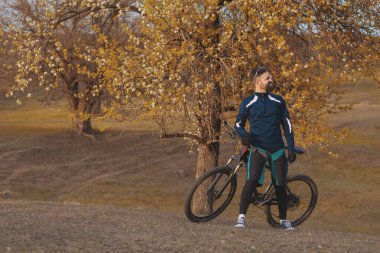 Bisikletçi sonbahar ormanlarında gezer ve park eder.