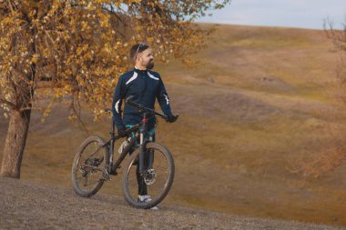 Bisikletçi sonbahar ormanlarında gezer ve park eder.