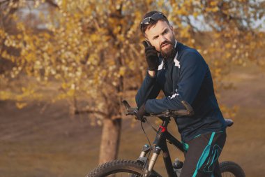 Bisikletçi sonbahar ormanlarında gezer ve park eder.