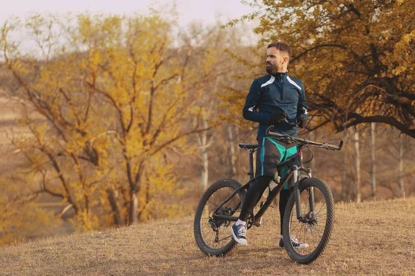 Bisikletçi sonbahar ormanlarında gezer ve park eder.