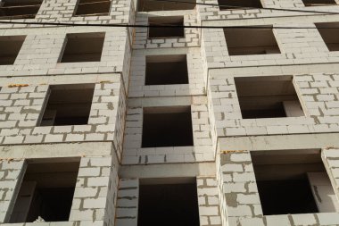 Mavi gökyüzünün arka planında yapım aşamasındaki çok katlı bir bina ve vinç.