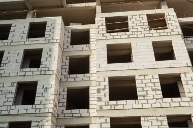 Mavi gökyüzünün arka planında yapım aşamasındaki çok katlı bir bina ve vinç.