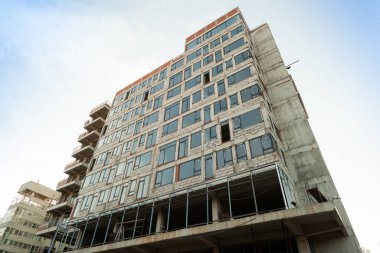 Mavi gökyüzünün arka planında yapım aşamasındaki çok katlı bir bina ve vinç.