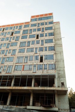 Mavi gökyüzünün arka planında yapım aşamasındaki çok katlı bir bina ve vinç.